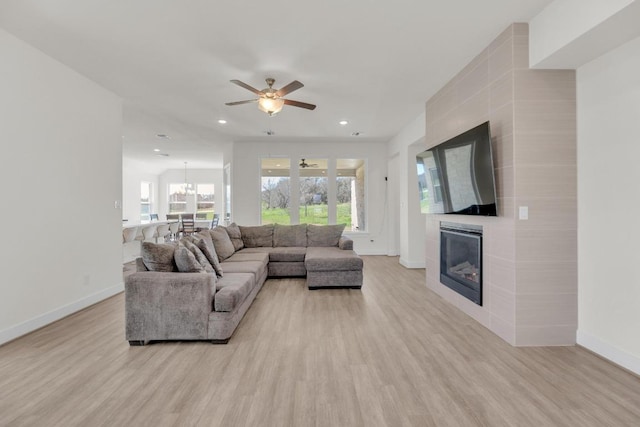 living room with light wood-type flooring, recessed lighting, baseboards, and a tile fireplace