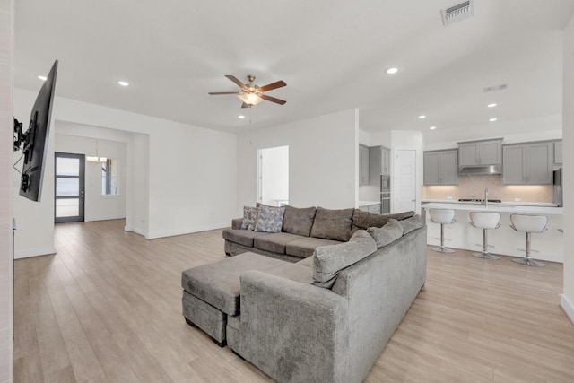 living room with light wood-type flooring, visible vents, a ceiling fan, and recessed lighting