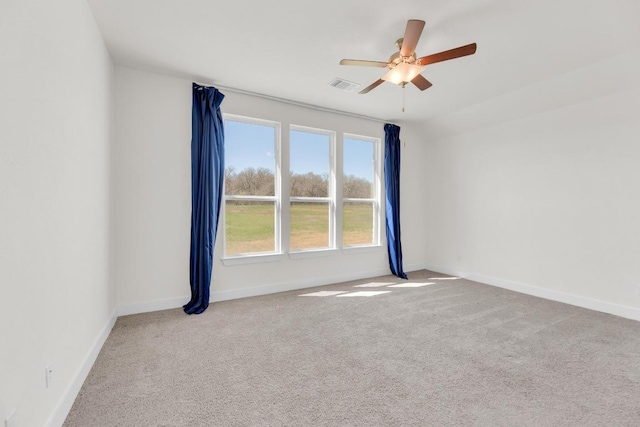 spare room featuring carpet floors, baseboards, visible vents, and a ceiling fan