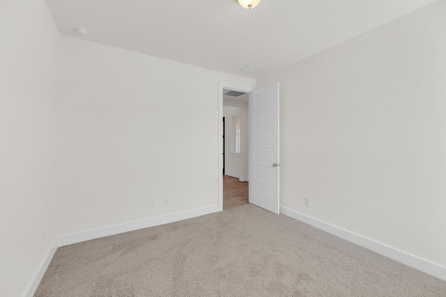 spare room with carpet floors, visible vents, and baseboards