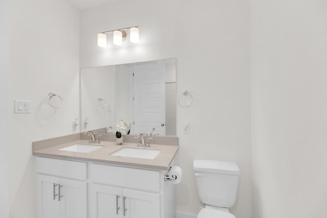 bathroom with a sink, toilet, and double vanity