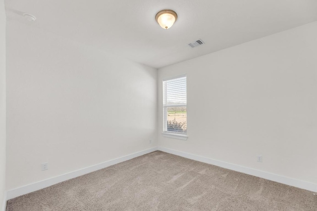 empty room with baseboards, visible vents, and light colored carpet