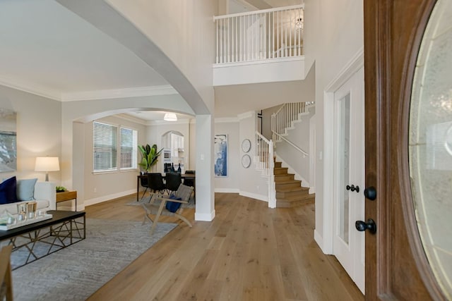 entryway with crown molding, stairs, baseboards, and wood finished floors