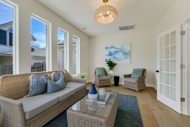 interior space featuring a chandelier, visible vents, baseboards, and wood finished floors