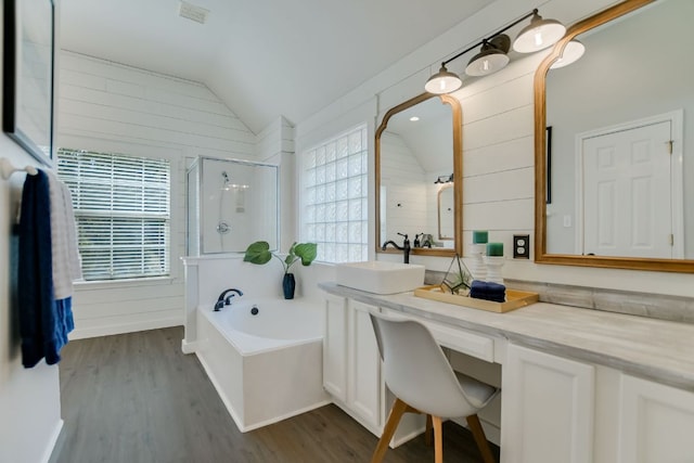 full bath featuring lofted ceiling, a stall shower, a garden tub, and wood finished floors