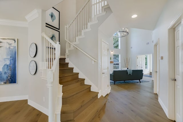 stairway featuring a high ceiling, wood finished floors, visible vents, and baseboards