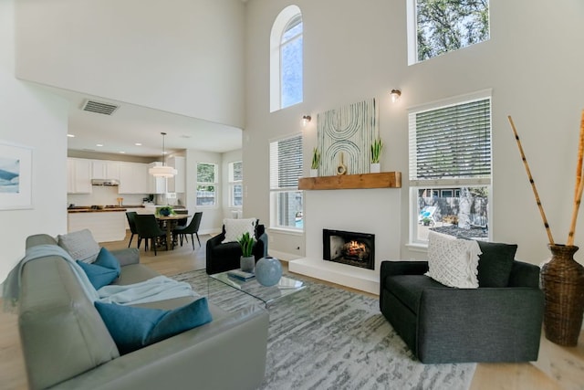 living area featuring a wealth of natural light, visible vents, a fireplace, and light wood finished floors