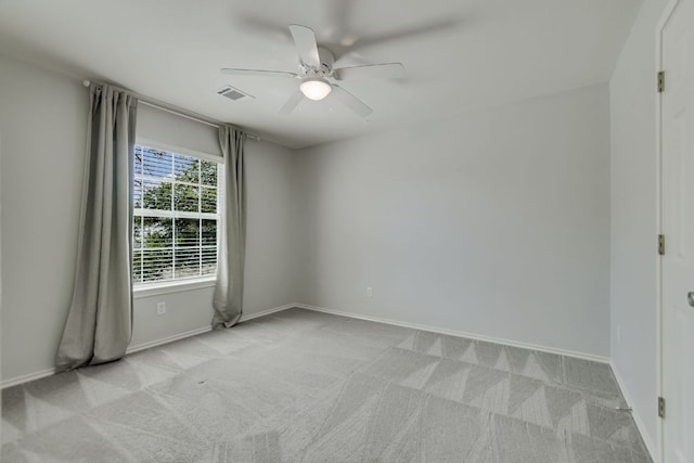 empty room with light carpet, ceiling fan, visible vents, and baseboards