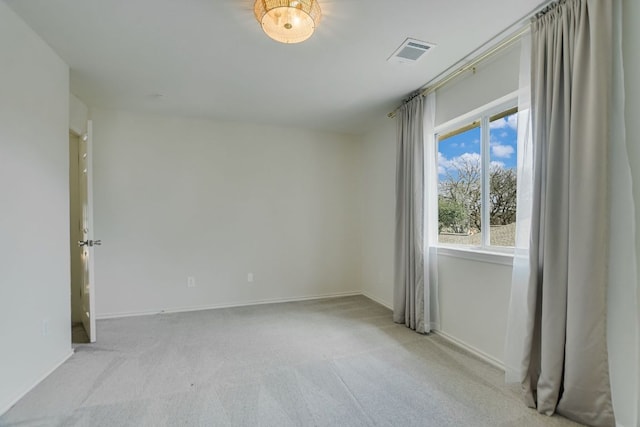 carpeted spare room featuring baseboards and visible vents