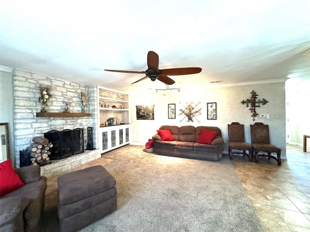 living room featuring ceiling fan, built in shelves, a stone fireplace, visible vents, and crown molding