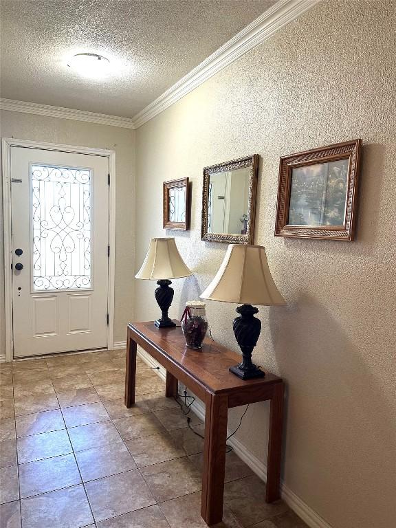 foyer featuring baseboards, ornamental molding, a textured ceiling, and a textured wall