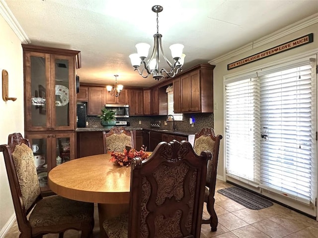 dining space featuring light tile patterned floors, ornamental molding, a textured ceiling, and an inviting chandelier