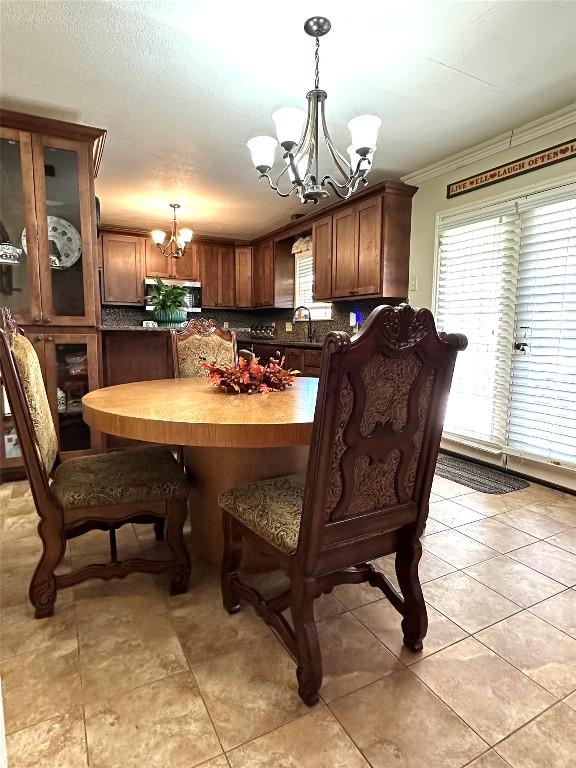 dining area featuring light tile patterned flooring, crown molding, and an inviting chandelier