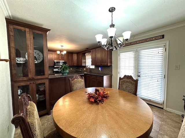 dining space featuring crown molding, a notable chandelier, light tile patterned flooring, a textured ceiling, and baseboards