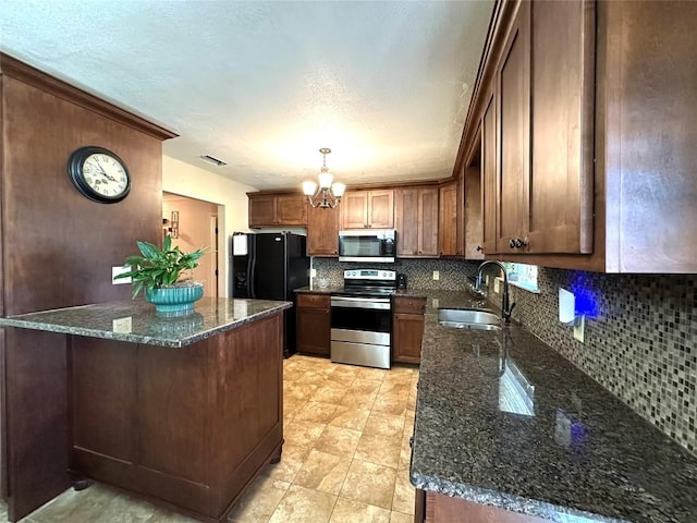 kitchen with stainless steel appliances, a sink, visible vents, tasteful backsplash, and dark stone countertops