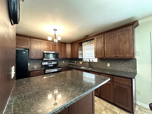 kitchen with stainless steel appliances, a sink, backsplash, and an inviting chandelier