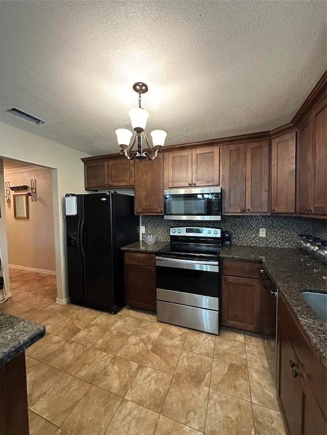 kitchen featuring visible vents, a notable chandelier, stainless steel appliances, pendant lighting, and backsplash