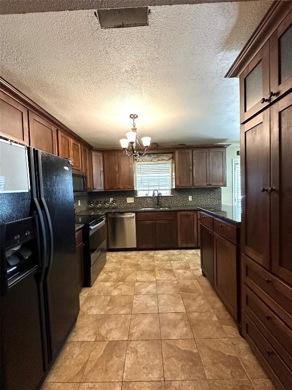 kitchen with a notable chandelier, stainless steel appliances, a sink, tasteful backsplash, and dark countertops