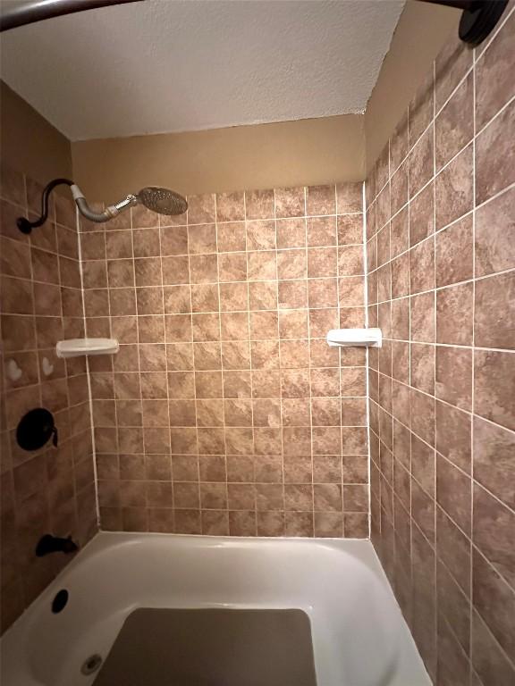 full bath with shower / bath combination and a textured ceiling