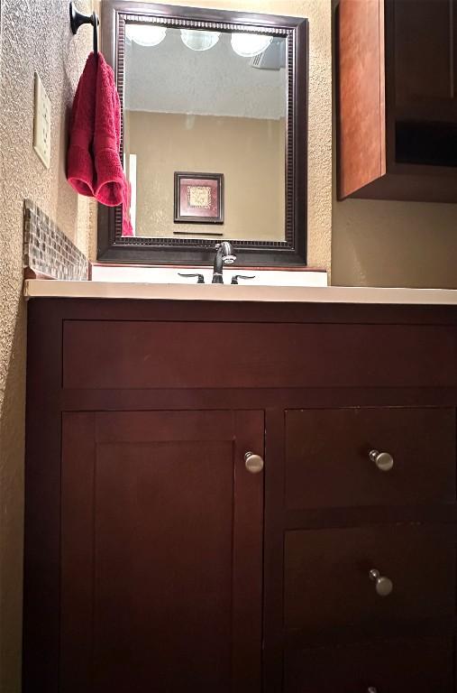 bathroom featuring vanity and a textured wall