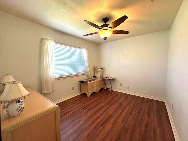 office area with dark wood-style flooring, a ceiling fan, and baseboards