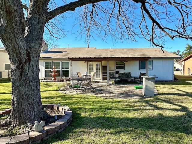 rear view of property with a chimney, a lawn, french doors, and a patio