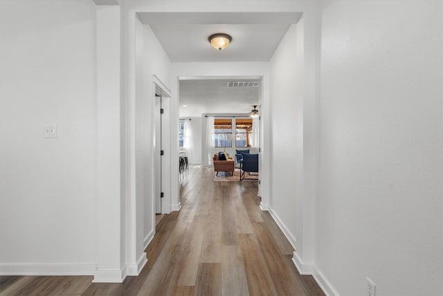 hallway with visible vents, baseboards, and wood finished floors