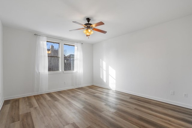 spare room featuring ceiling fan, baseboards, and wood finished floors