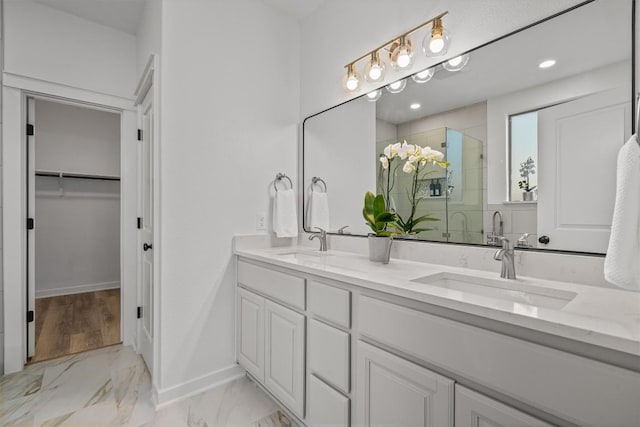 bathroom with marble finish floor, a sink, a shower stall, and a spacious closet