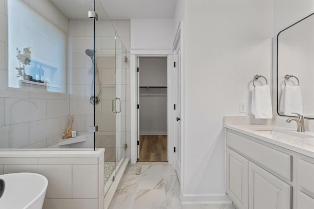 full bath with a stall shower, a soaking tub, marble finish floor, a spacious closet, and vanity