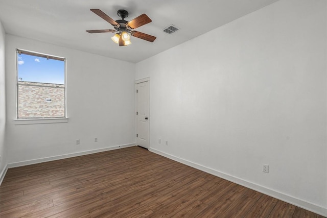 empty room with dark wood-style floors, visible vents, baseboards, and a ceiling fan