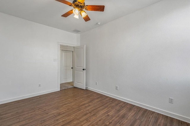 empty room featuring a ceiling fan, dark wood-style flooring, visible vents, and baseboards