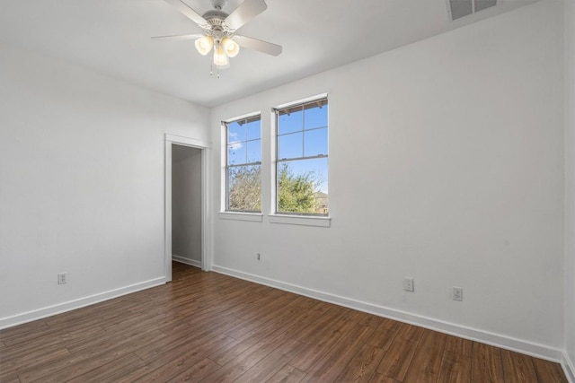 spare room featuring baseboards, dark wood finished floors, and ceiling fan