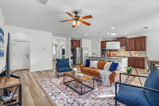 living room featuring ceiling fan, light wood-type flooring, and recessed lighting