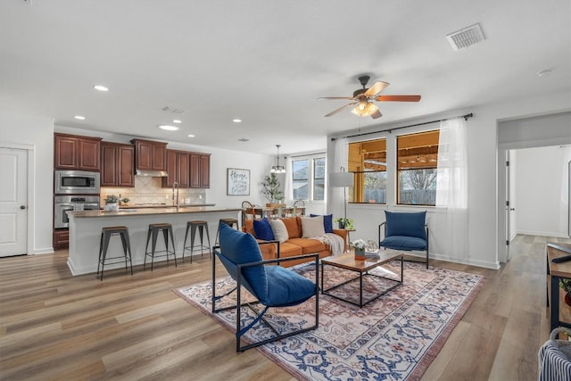 living area with visible vents, baseboards, ceiling fan, light wood-type flooring, and recessed lighting