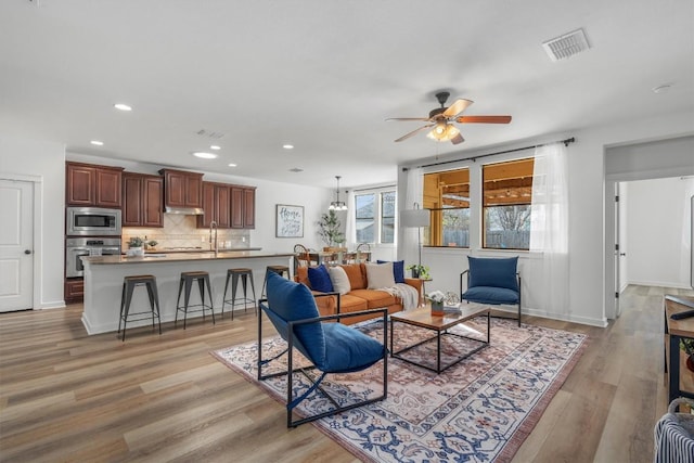 living room with ceiling fan, light wood-type flooring, and recessed lighting