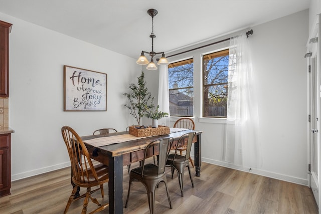 dining room featuring baseboards, an inviting chandelier, and light wood-style floors