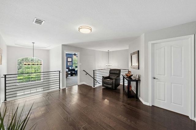 sitting room featuring baseboards, visible vents, wood finished floors, an upstairs landing, and ceiling fan with notable chandelier