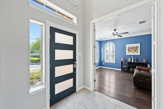 foyer entrance featuring baseboards, a wealth of natural light, visible vents, and crown molding