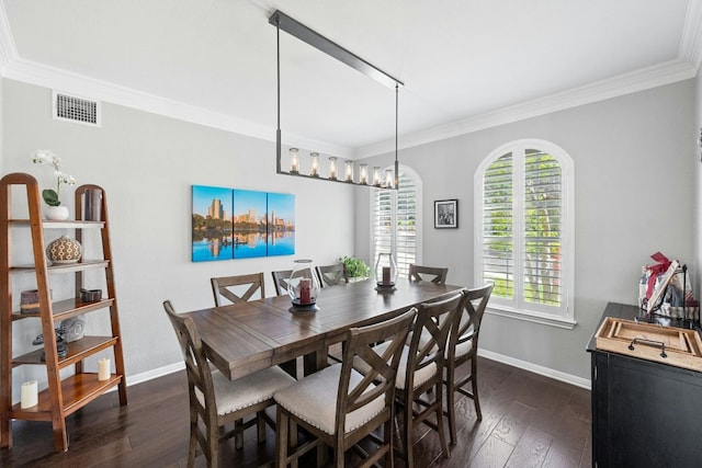 dining space featuring dark wood-type flooring, visible vents, crown molding, and baseboards