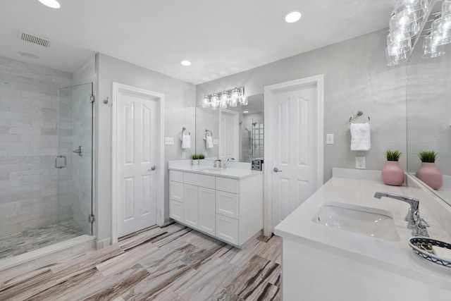 bathroom with a stall shower, two vanities, a sink, and recessed lighting