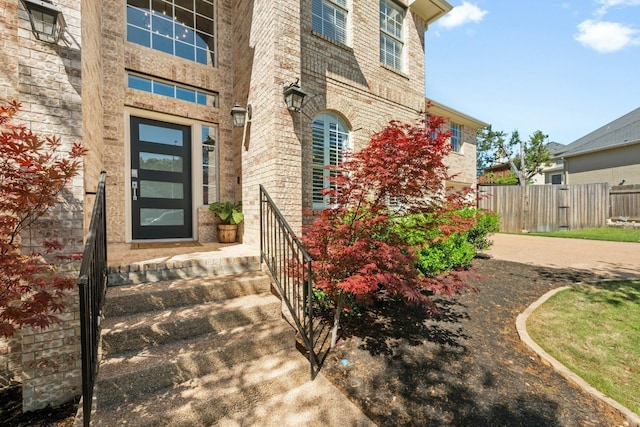 property entrance featuring brick siding and fence