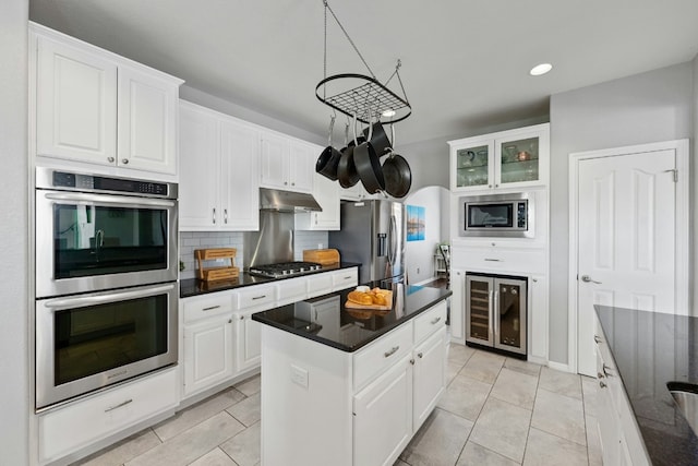 kitchen featuring appliances with stainless steel finishes, backsplash, white cabinets, and under cabinet range hood