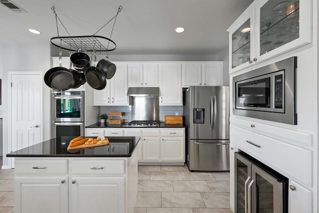 kitchen featuring dark countertops, visible vents, decorative backsplash, appliances with stainless steel finishes, and under cabinet range hood