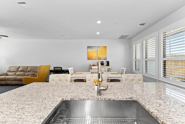 kitchen with light stone counters, visible vents, and a sink