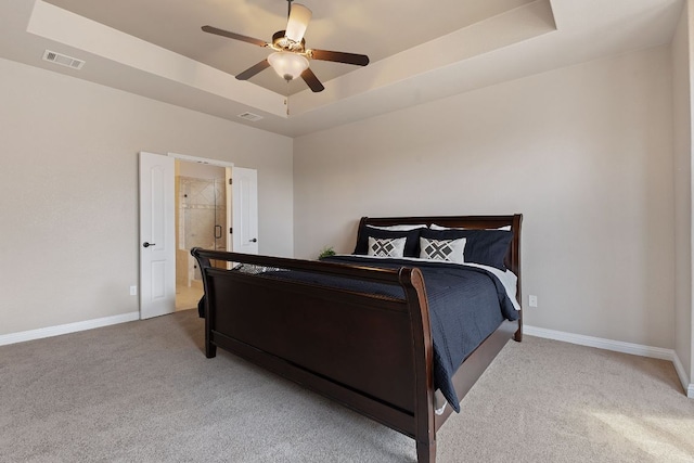 carpeted bedroom with visible vents, a raised ceiling, and baseboards