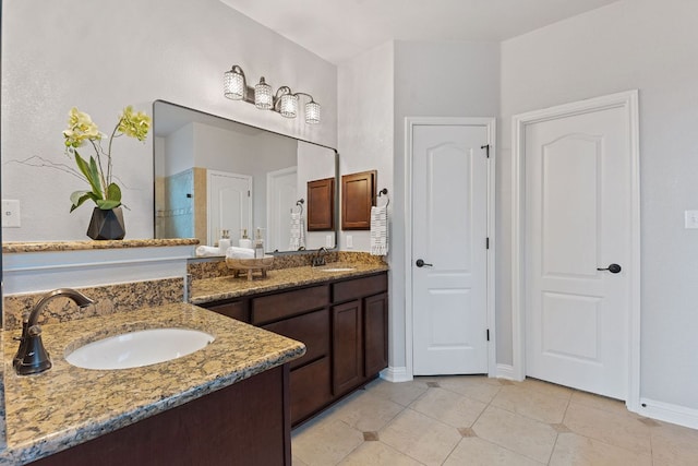 bathroom featuring tile patterned flooring, a sink, baseboards, and double vanity