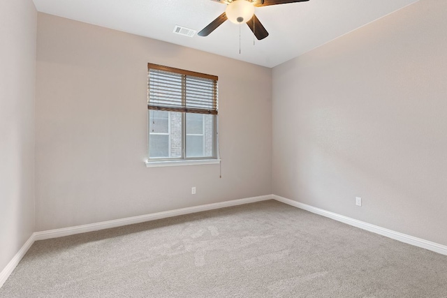 carpeted spare room featuring a ceiling fan, visible vents, and baseboards