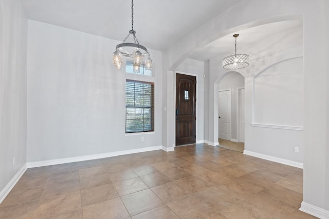 foyer entrance with arched walkways, baseboards, and an inviting chandelier
