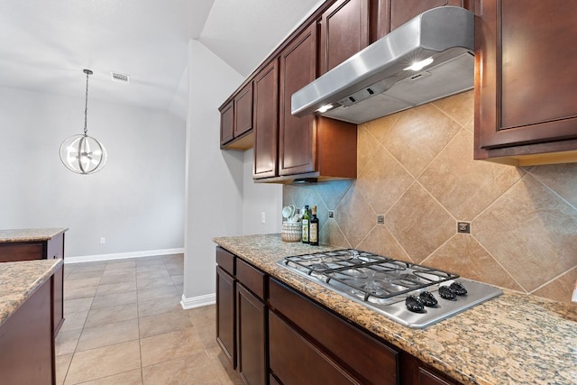 kitchen with under cabinet range hood, visible vents, stainless steel gas stovetop, tasteful backsplash, and pendant lighting